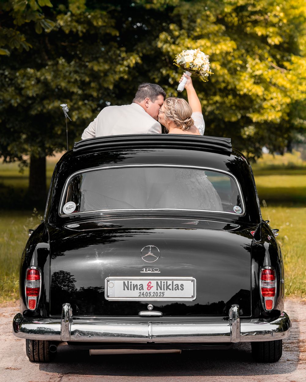 Hochzeitspaar steht lachend im Auto – moderne und kreative Hochzeitsfotografie in Karlsruhe.