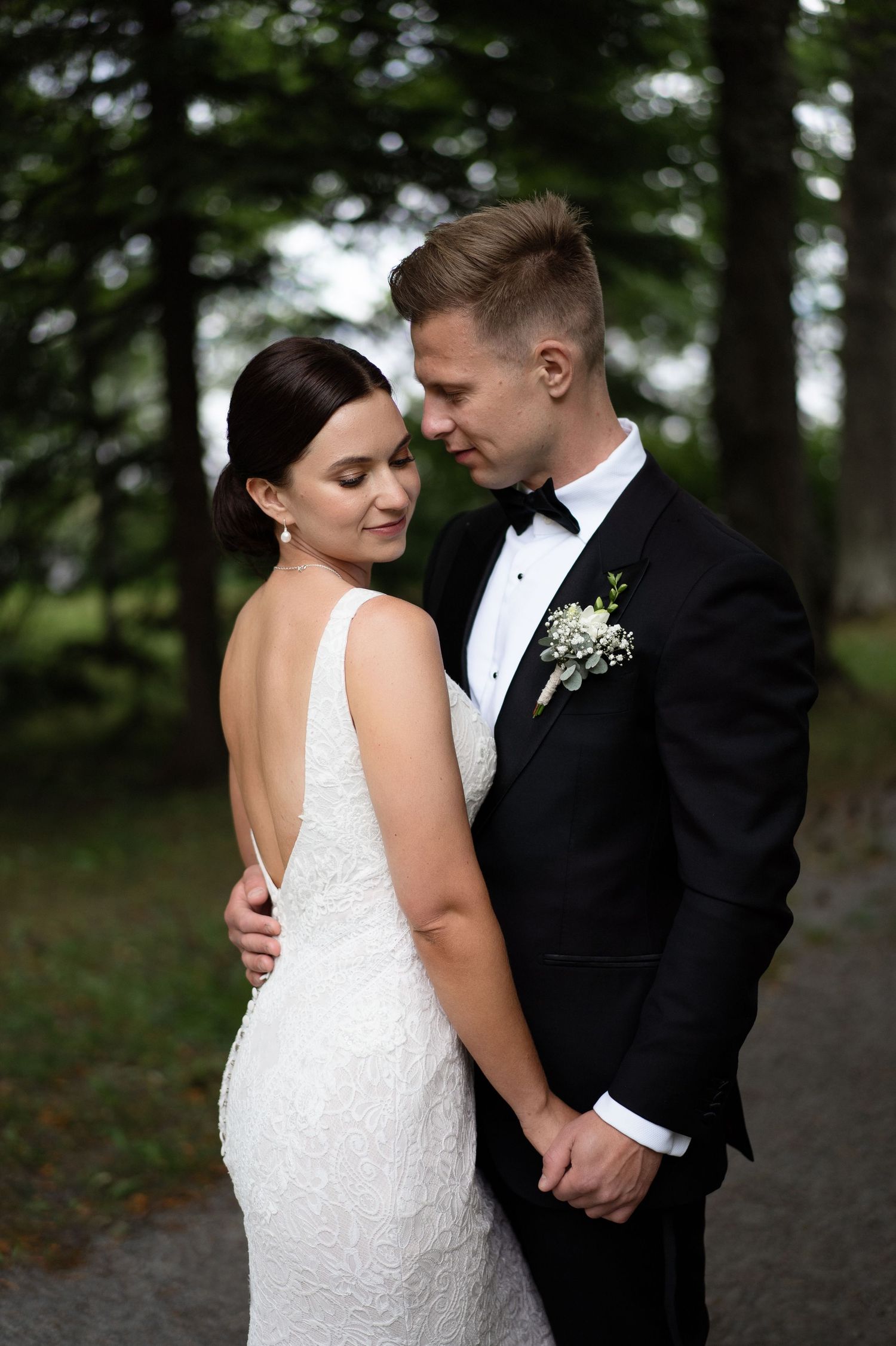 An intimate outdoor wedding portrait with natural forest lighting and classic formal attire.
