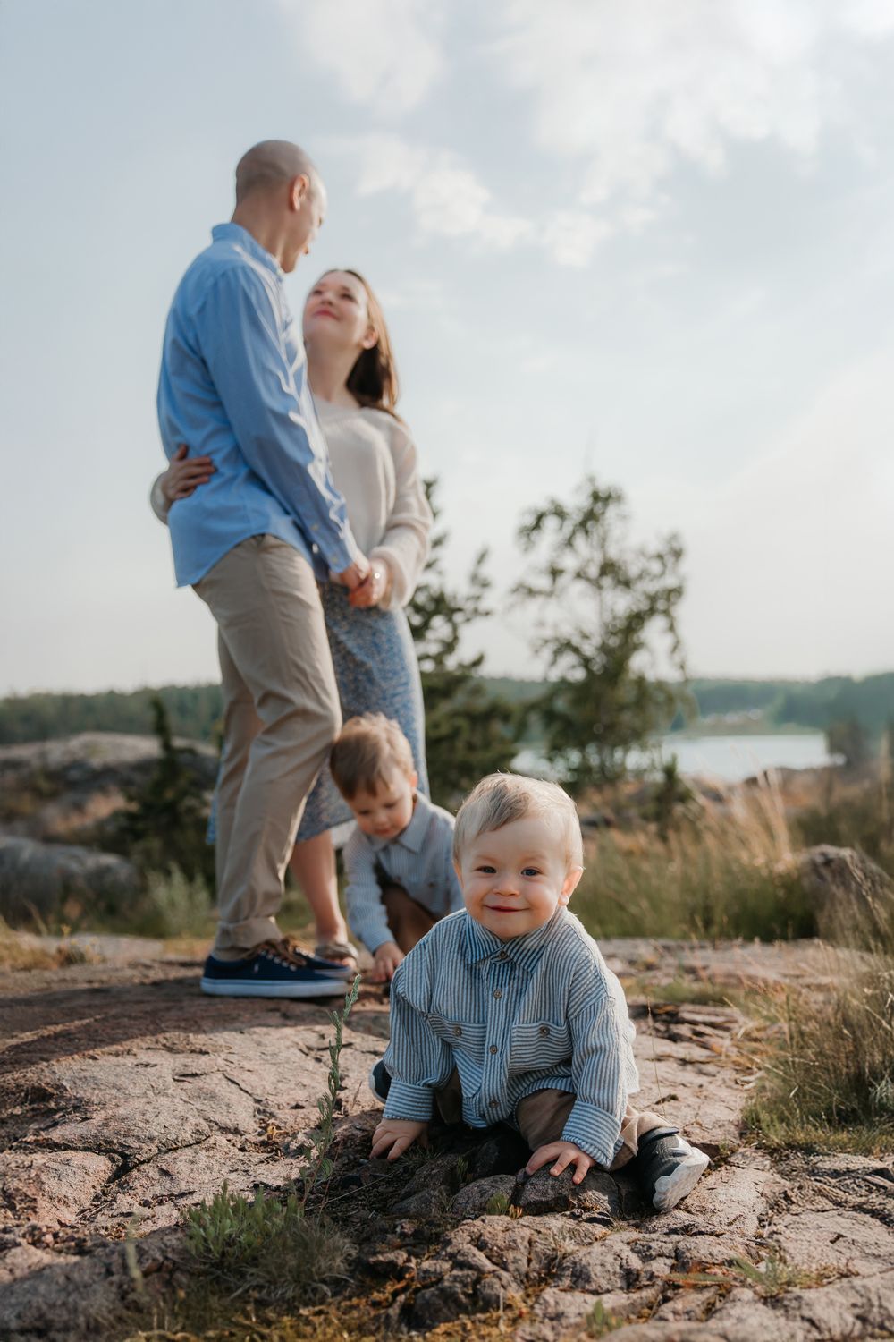 A candid family moment captured on rocky coastal terrain with water views.