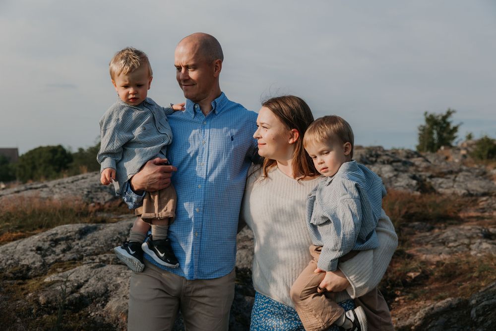Family enjoying time together on rocky coastal terrain at sunset.