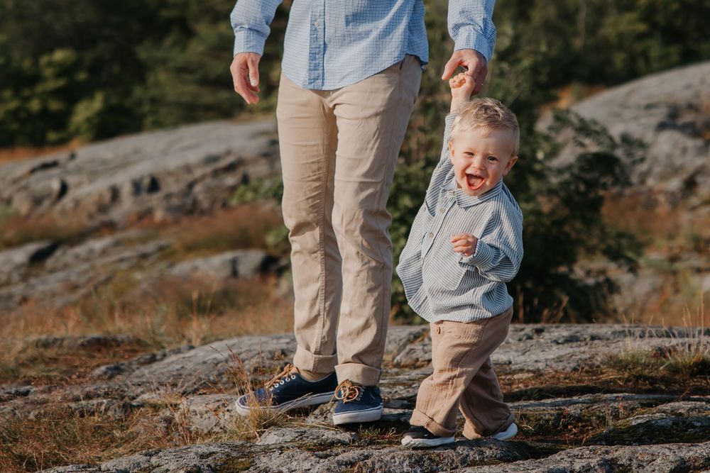 A small child holds hands while walking on rocky coastal terrain.