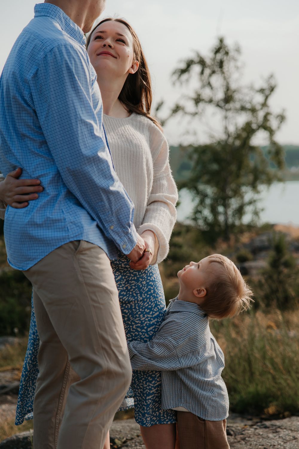 Family sharing tender moments together outdoors against natural backdrop.