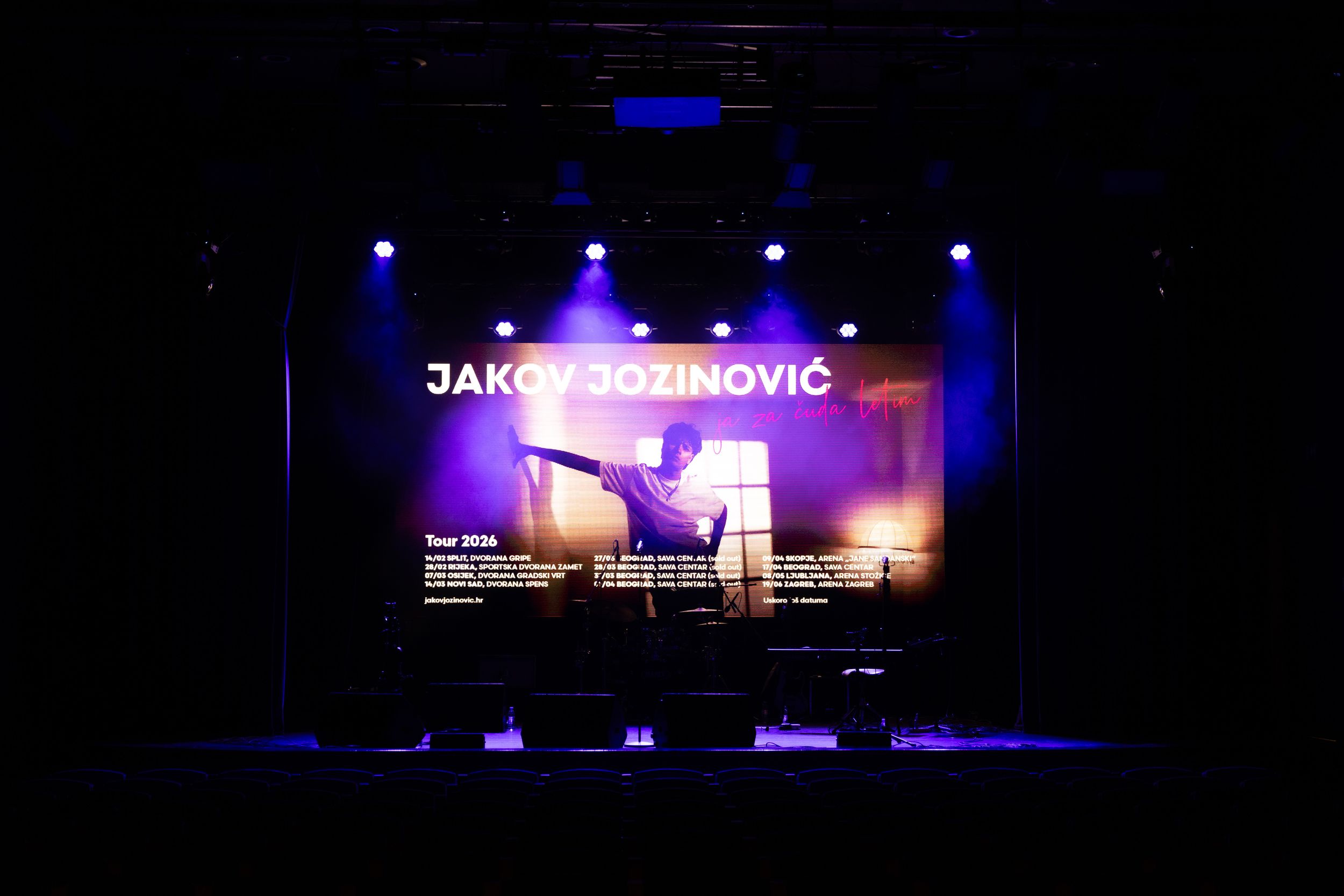 A stage performance setup with dark lighting and blue accent lights illuminating text displayed on a screen.