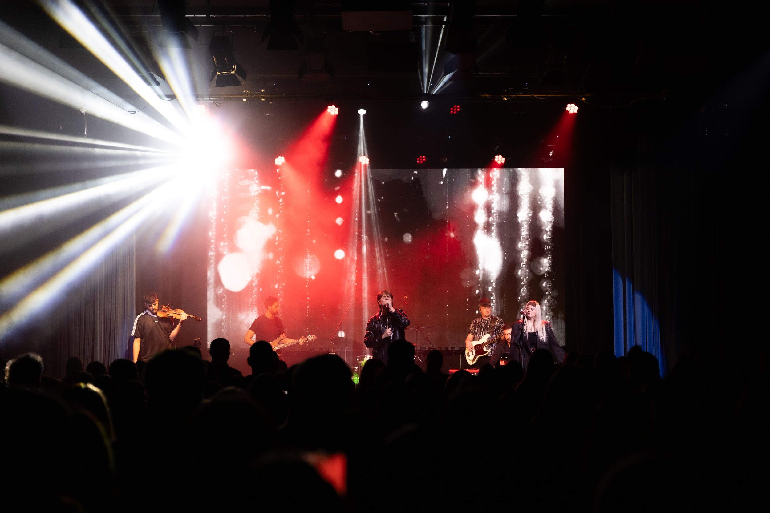 Concert stage illuminated with dramatic white and red lighting effects during a live performance.
