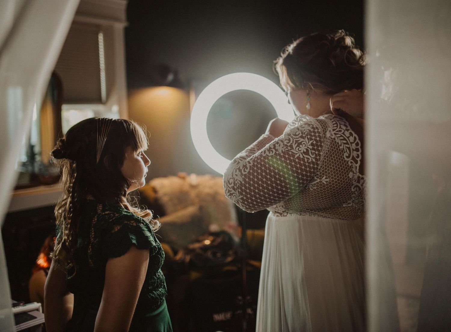 Intimate wedding preparation scene with soft lighting and flowing white dress details.