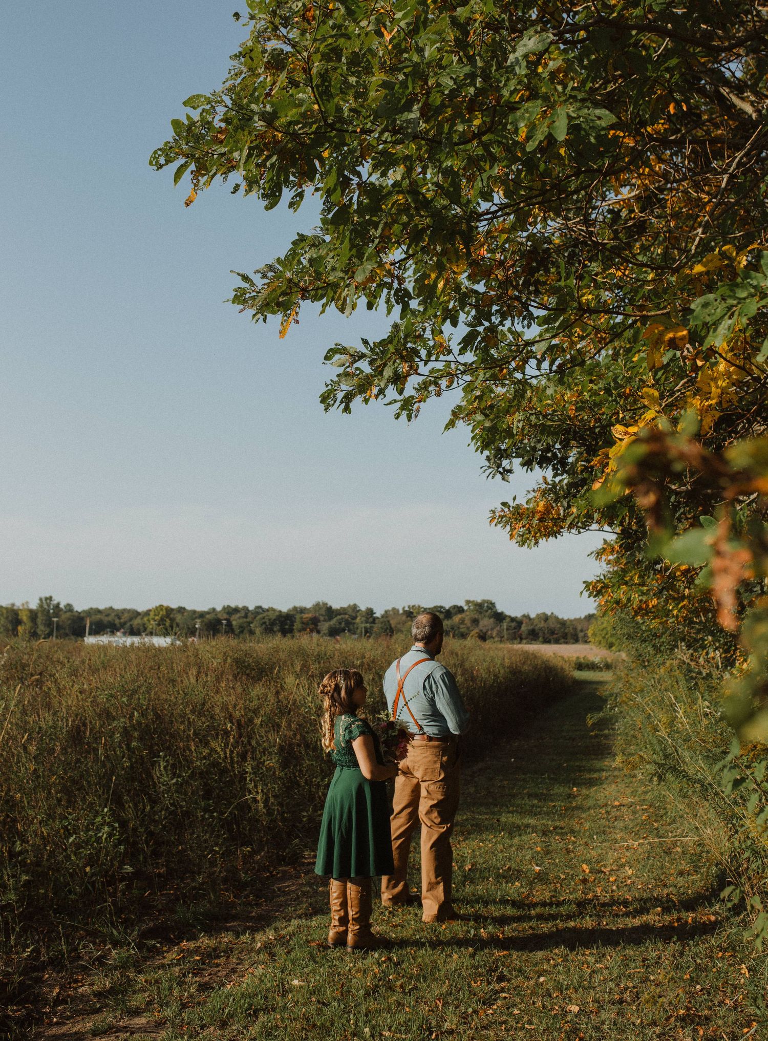 Wedding party walking through an autumn orchard with trees and golden sunlight.
