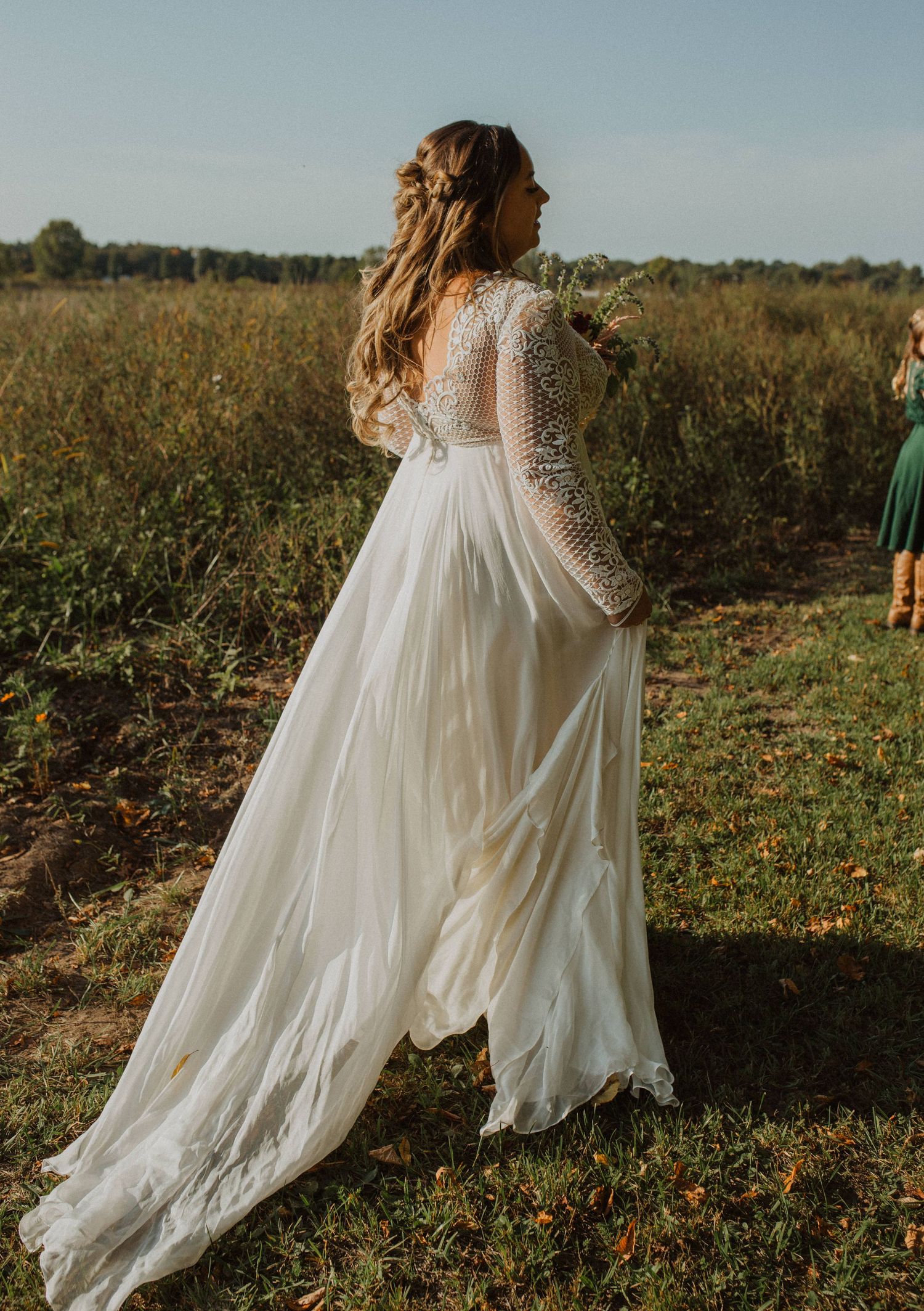 Flowing white wedding dress moving in the breeze against a rustic outdoor landscape.