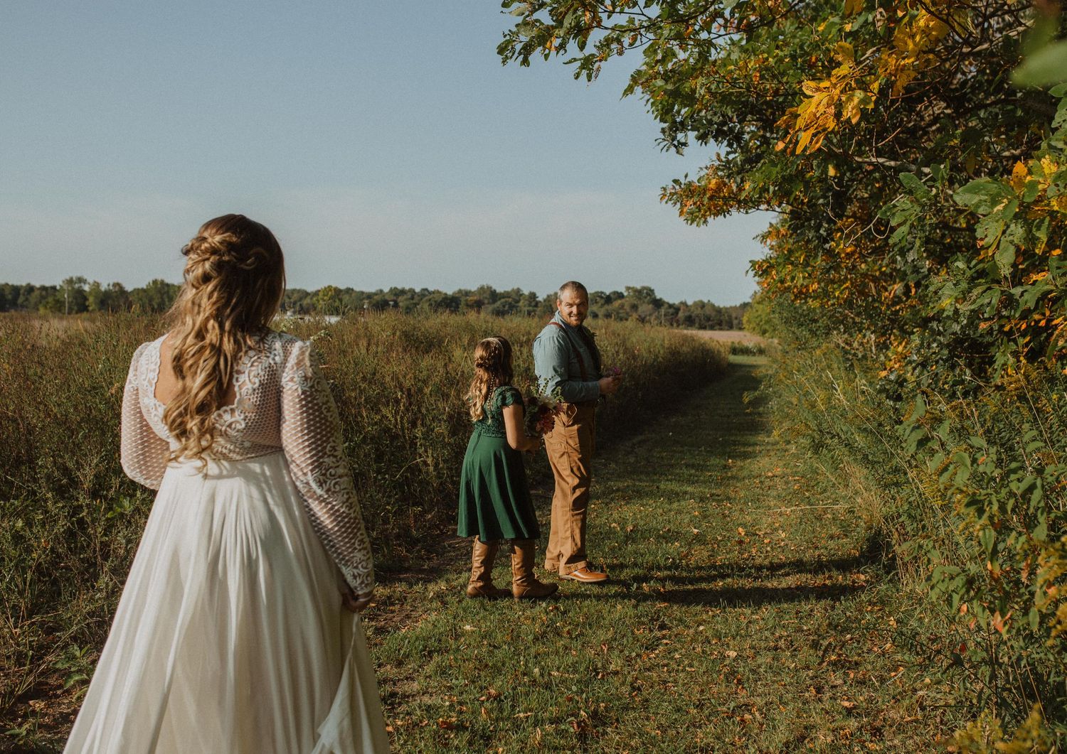 Wedding party walking through an orchard with fall foliage and golden light.