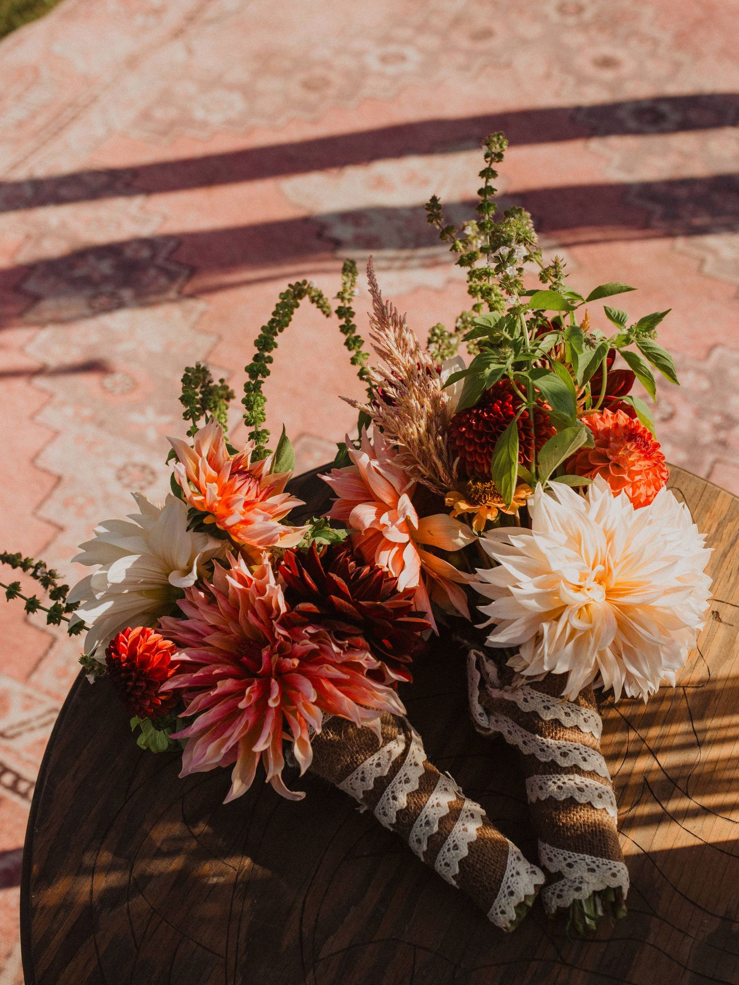 Floral arrangement with orange and white dahlias decorated with greenery on a rustic wooden surface.