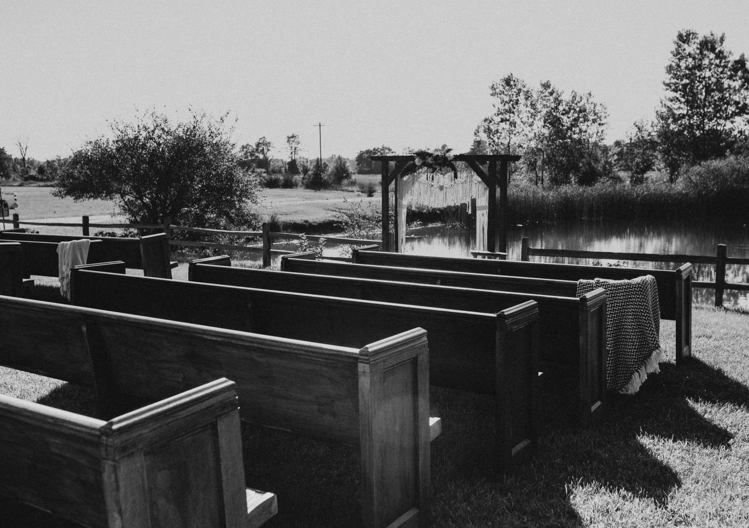 Row of raised garden beds in a landscaped outdoor setting with trees in the background.