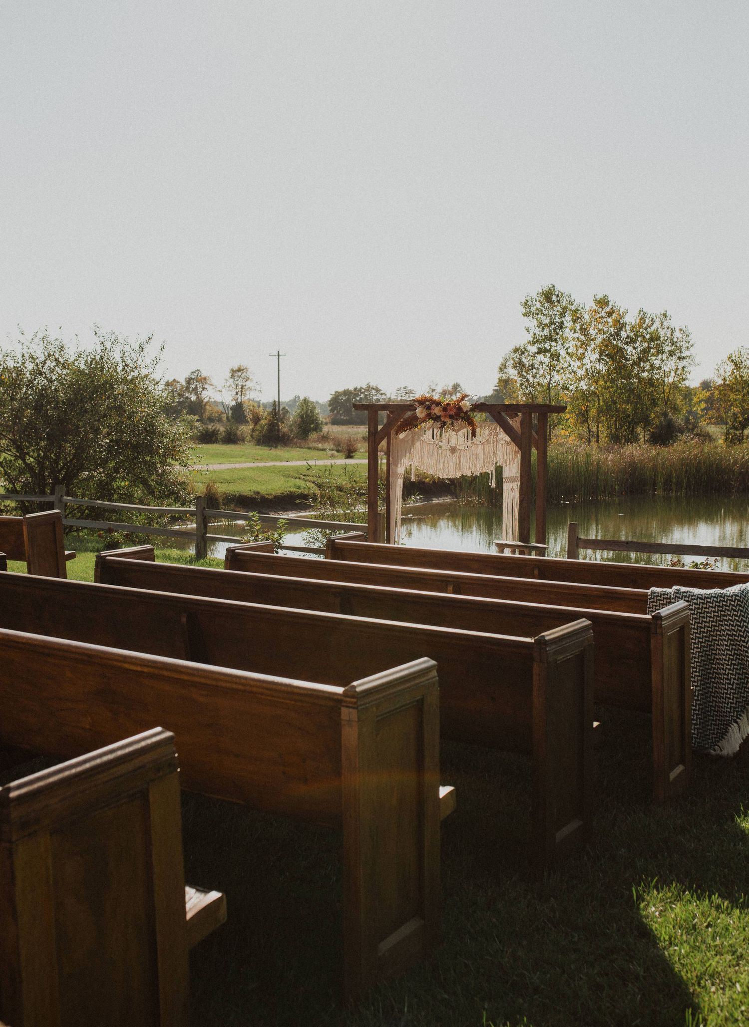 Panoramic view of wooden raised garden beds arranged in rows with a pond in the background.
