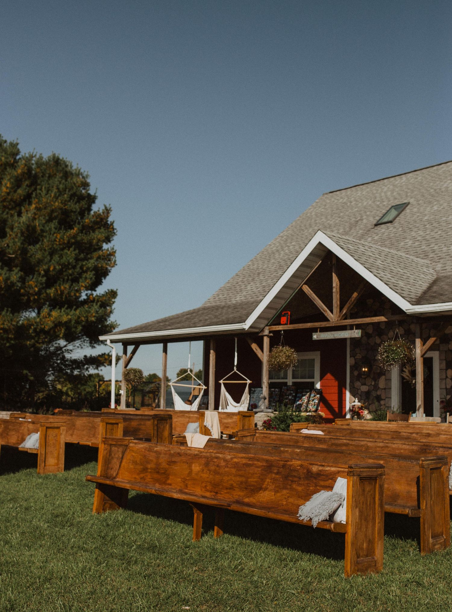 Rustic wooden benches arranged in rows outside a ranch-style building with timber accents.