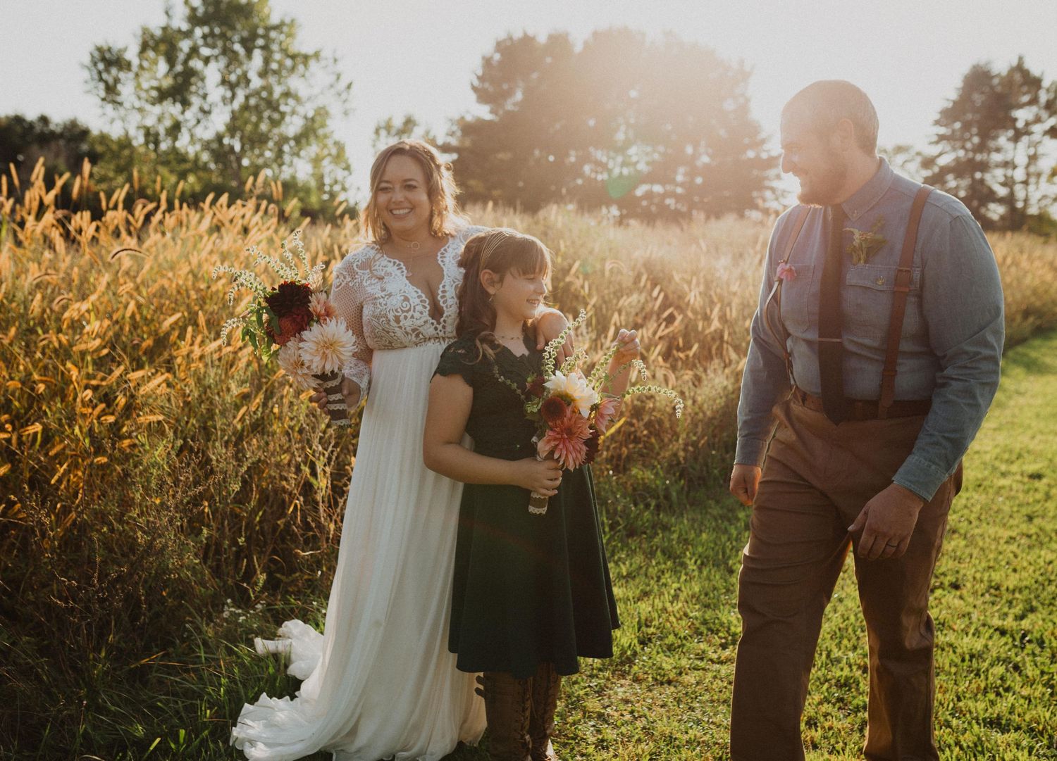 Wedding party gathers outdoors in natural setting with beautiful sunset lighting.