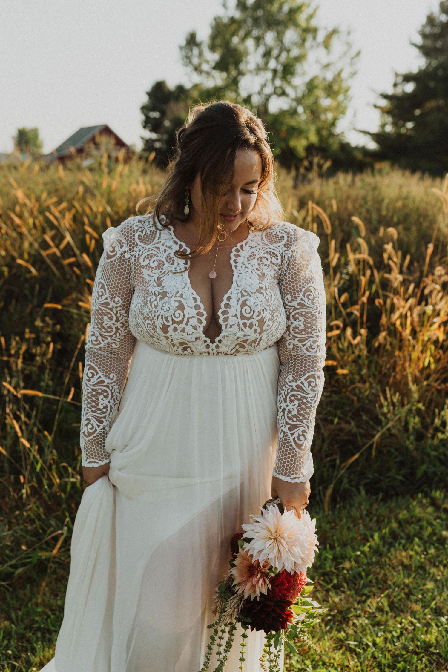 Delicate lace details and flowing fabric of a white wedding gown are captured in warm evening light.
