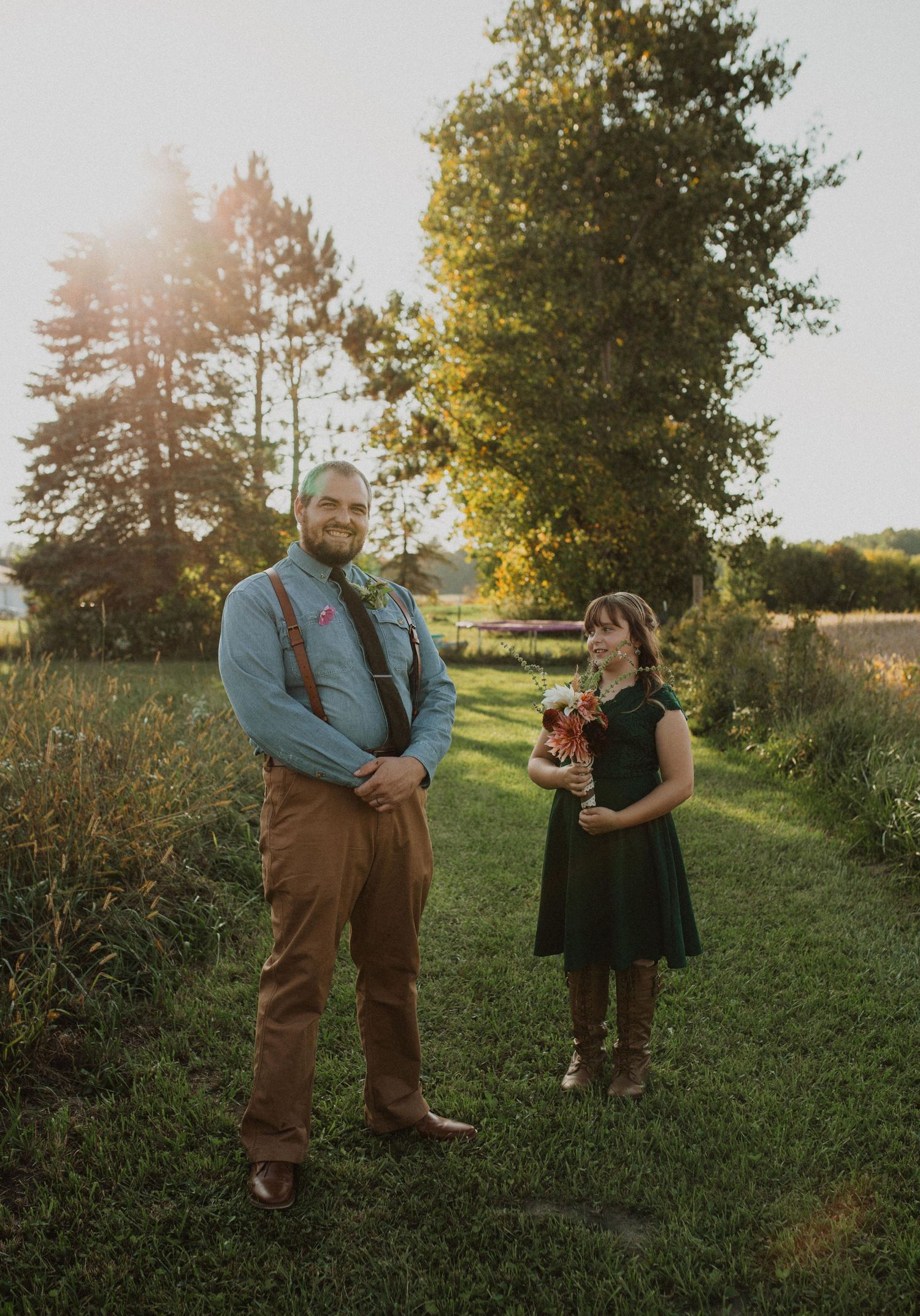 A couple shares a romantic moment in a grassy field during golden hour.