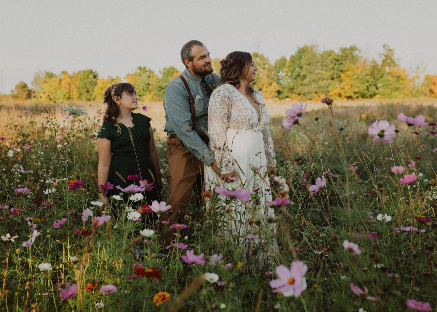A couple shares intimate moments in a wildflower field during golden hour sunset.