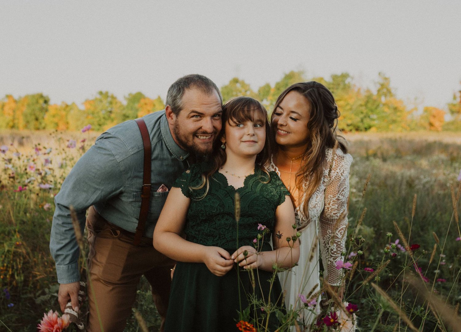 A group poses playfully together in a field of summer wildflowers.