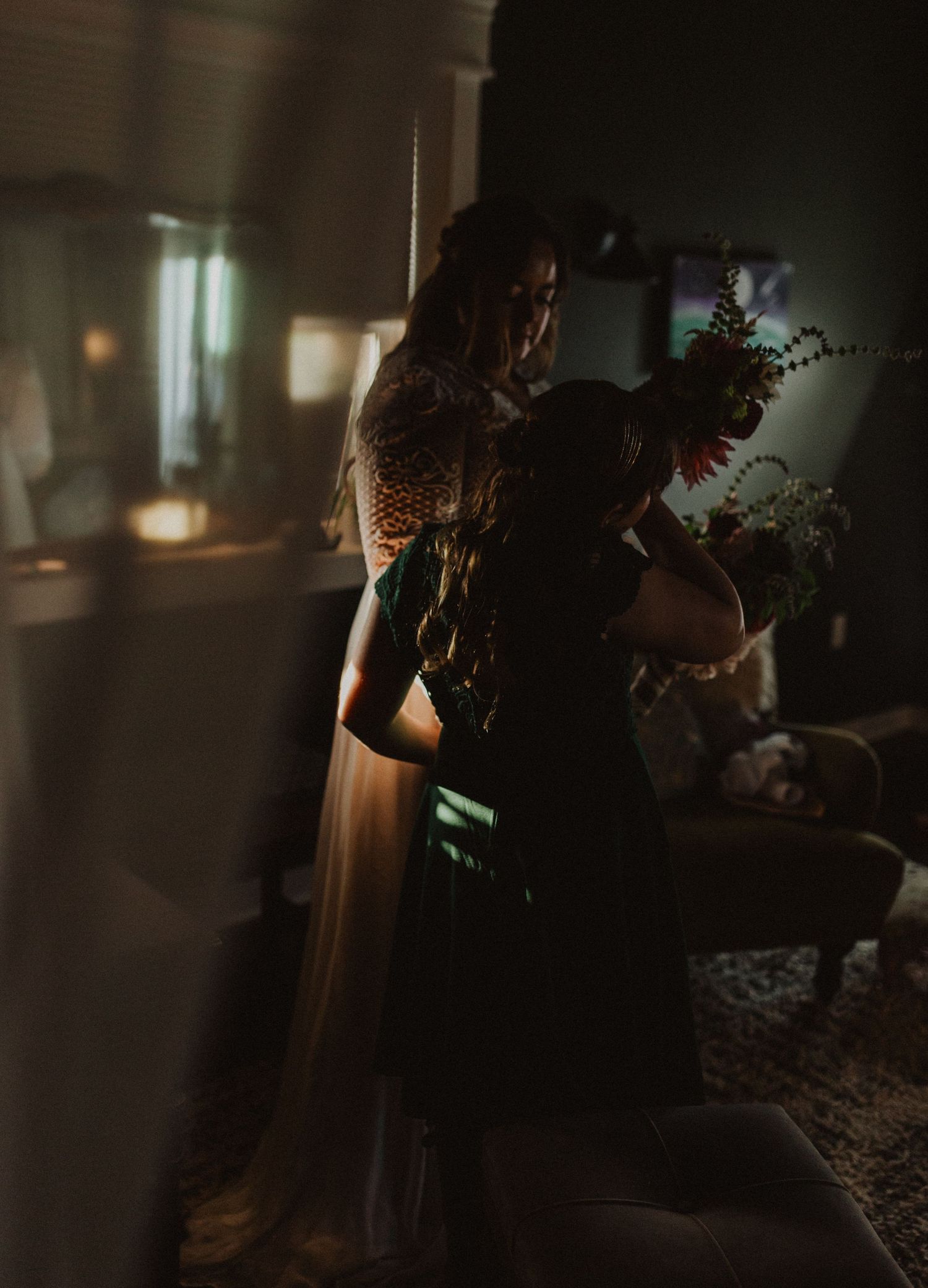 Silhouetted figures prepare in a dramatically lit interior space.