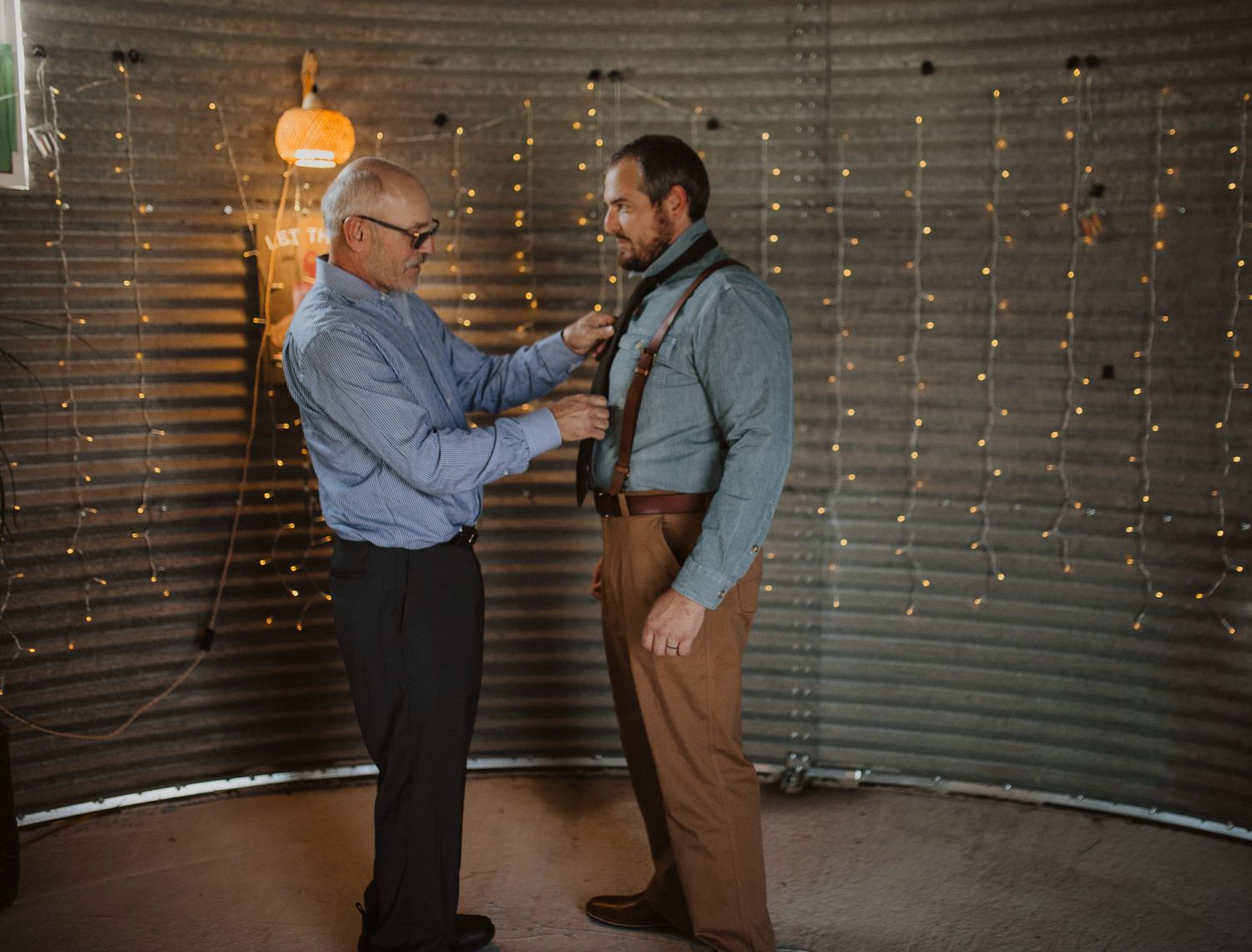 Candid moment between two people in a metal-walled room decorated with string lights.