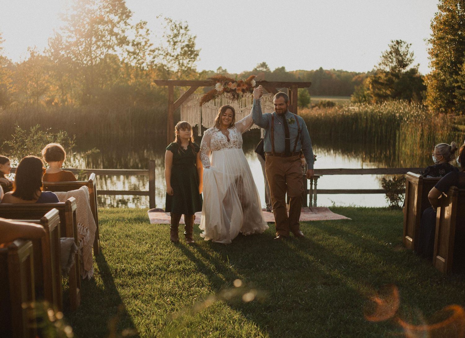 A joyful celebration moment during an outdoor wedding ceremony by the water.