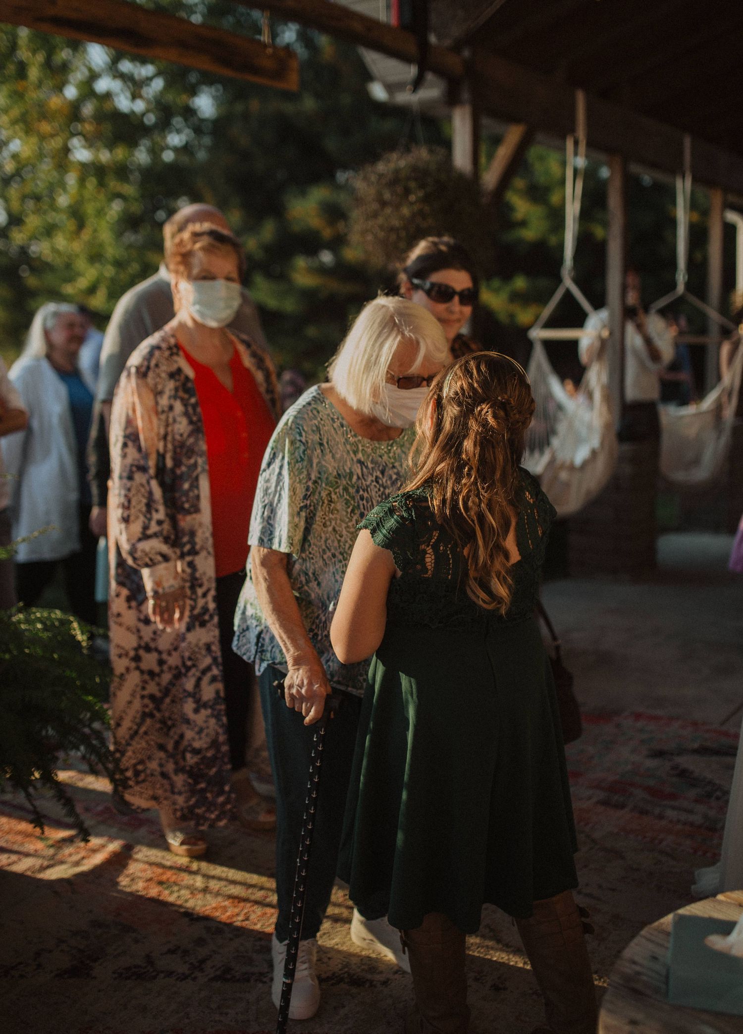 Wedding guests mingling at outdoor reception under covered venue space.