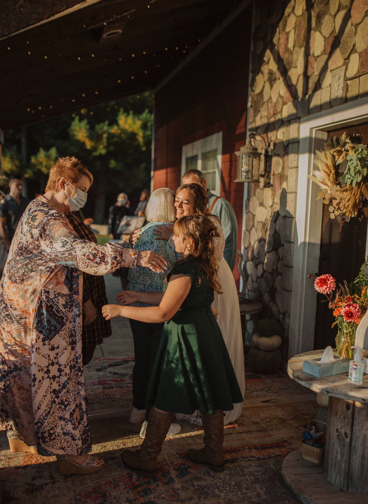 Wedding guests dance and celebrate at a rustic outdoor venue during golden hour.