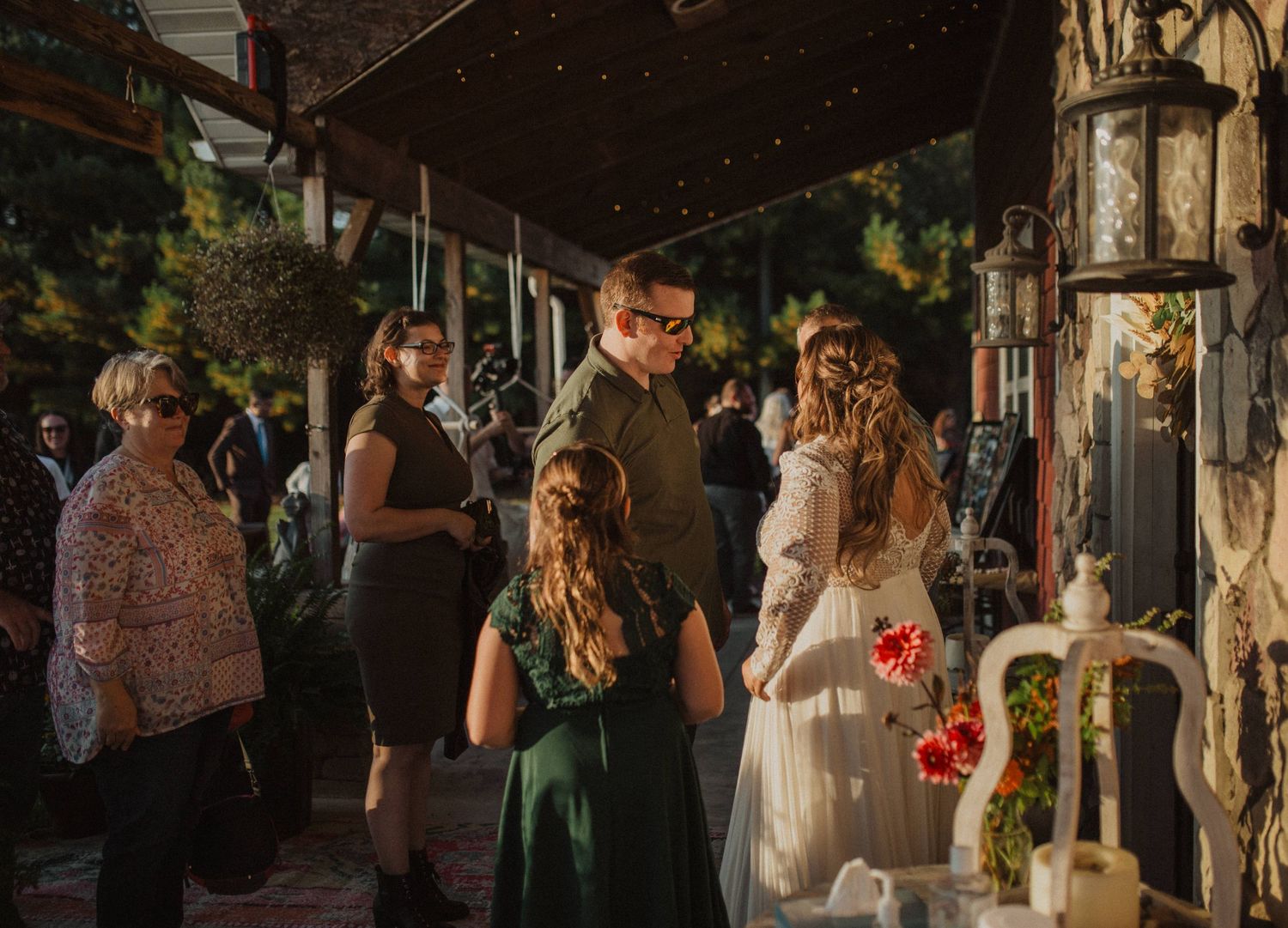 Wedding celebration at dusk with string lights and stone wall backdrop.