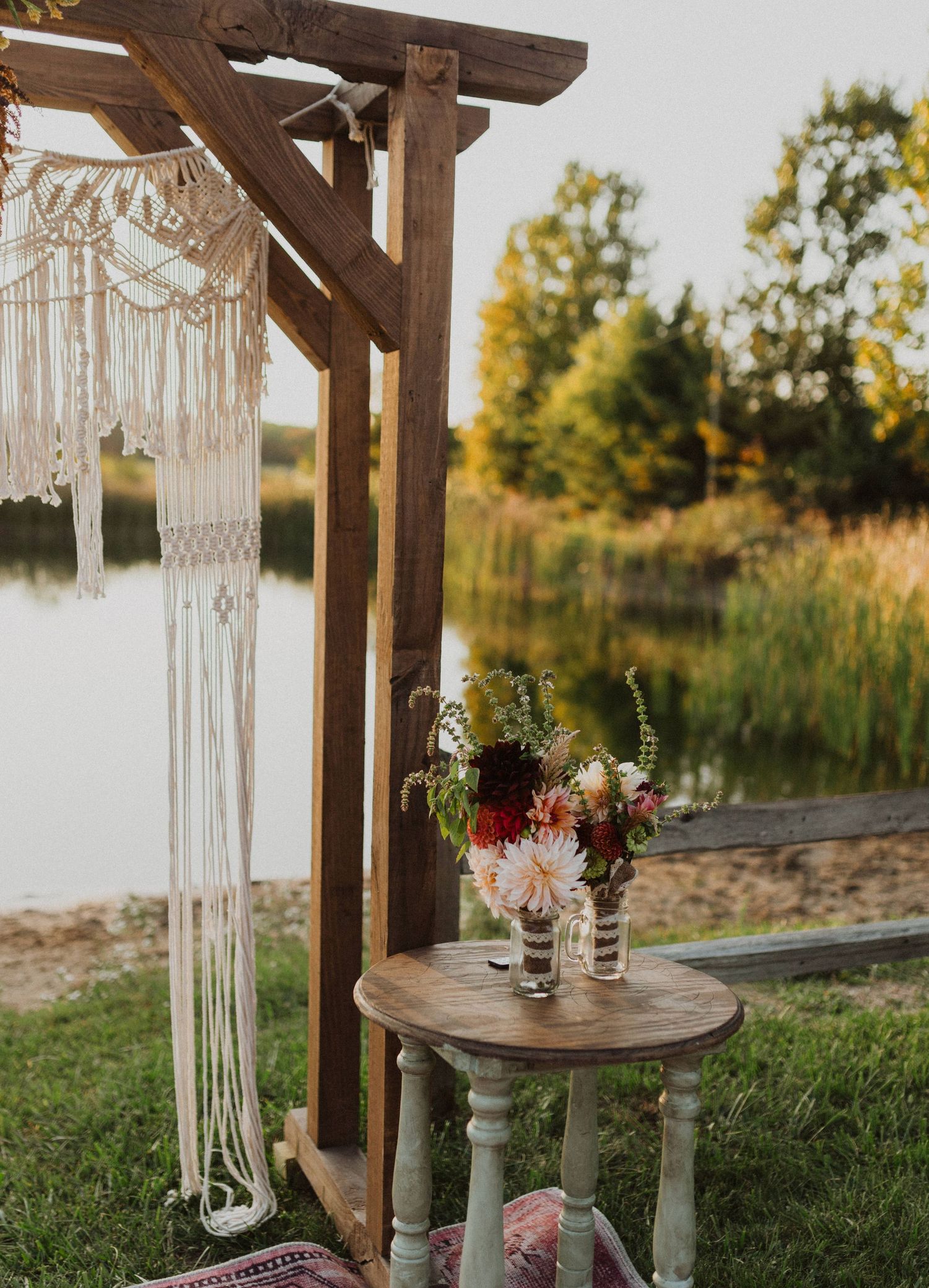 Rustic wooden pergola decorated with macrame hangings and floral arrangements for outdoor wedding.
