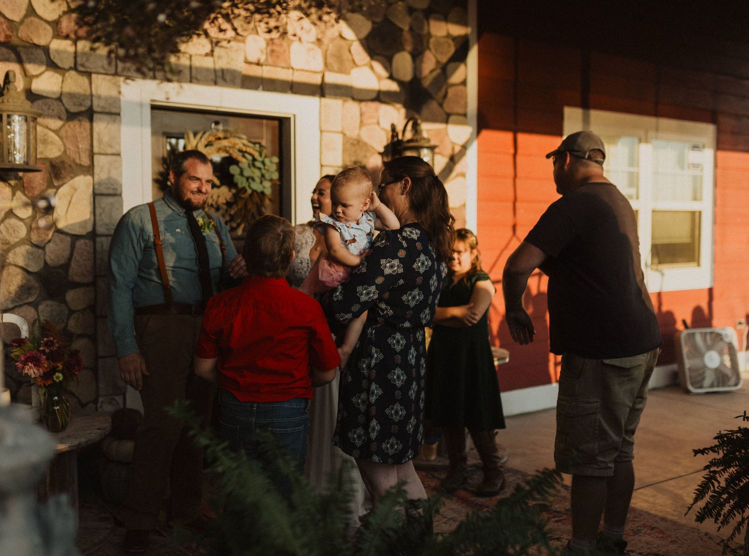 Evening gathering outside stone building with warm lighting and festive atmosphere.