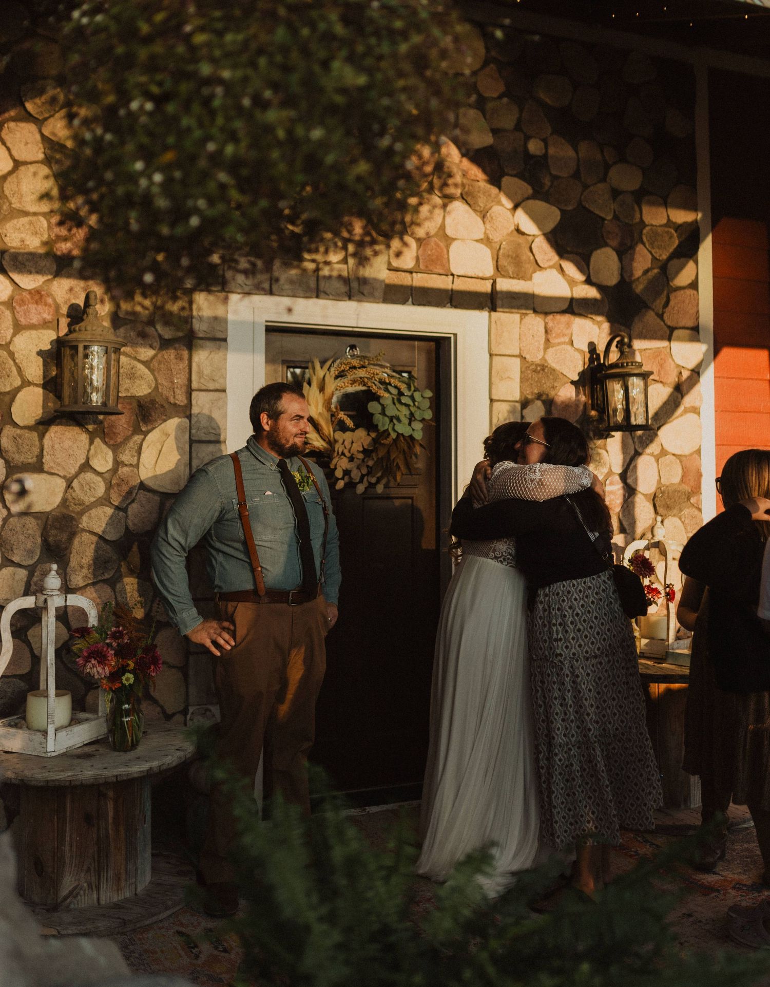 Wedding guests socializing outside stone venue during twilight hours.