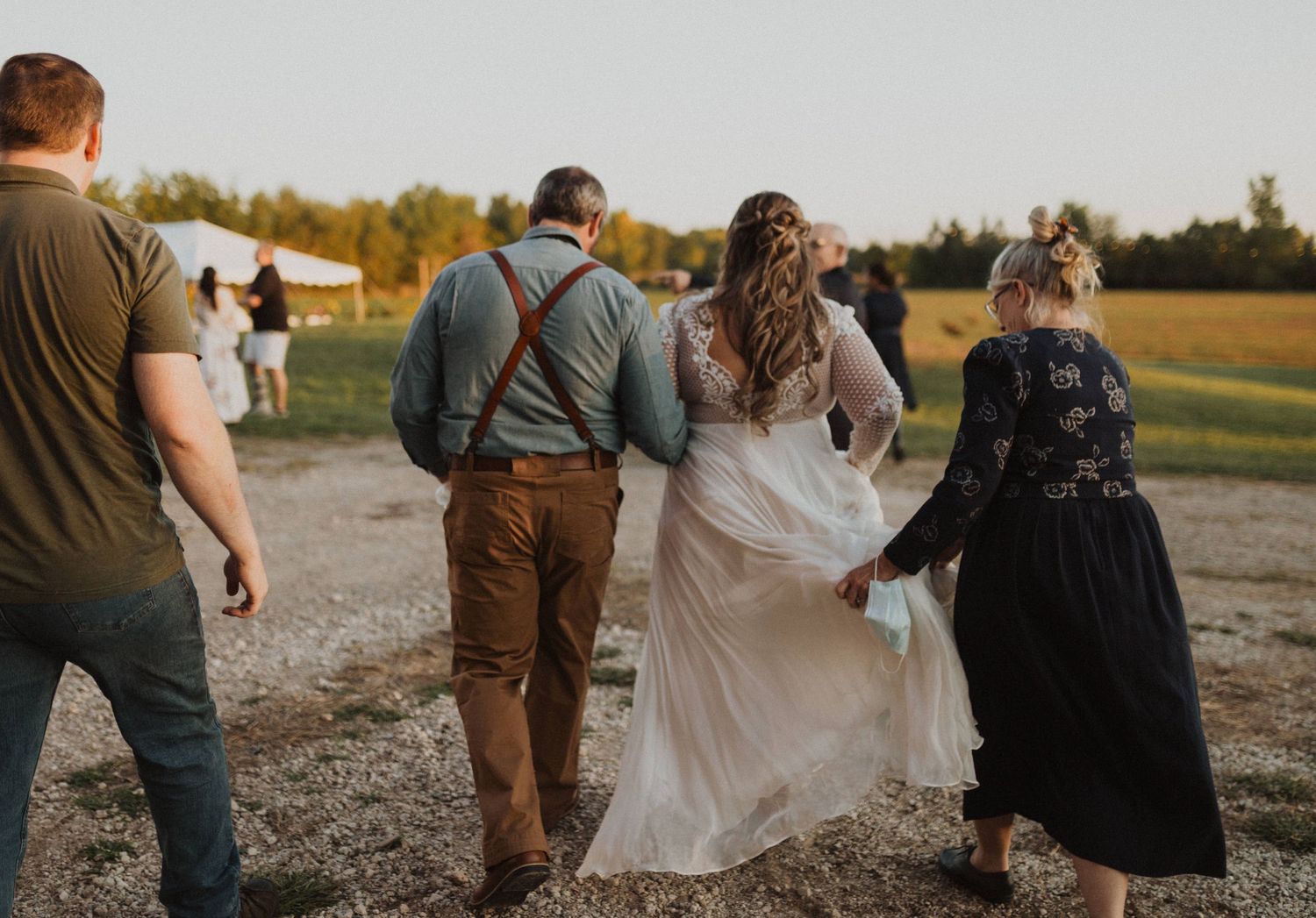 Wedding party walking together through field during golden hour photography session.