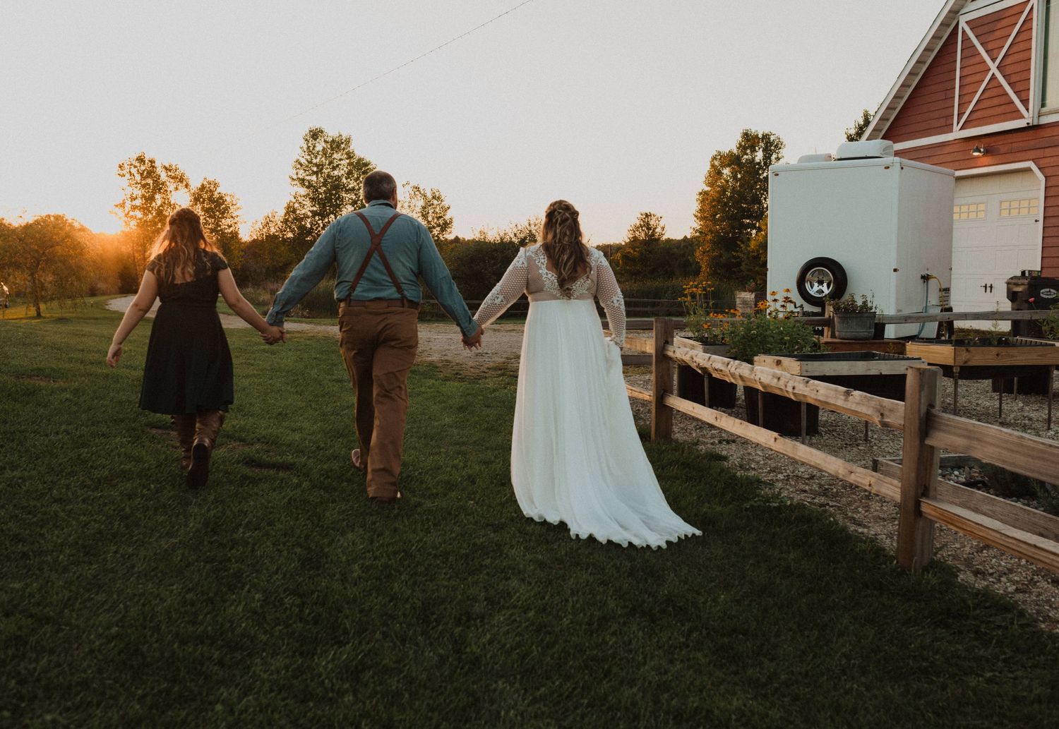 Wedding group walking along a wooden fence at golden hour.