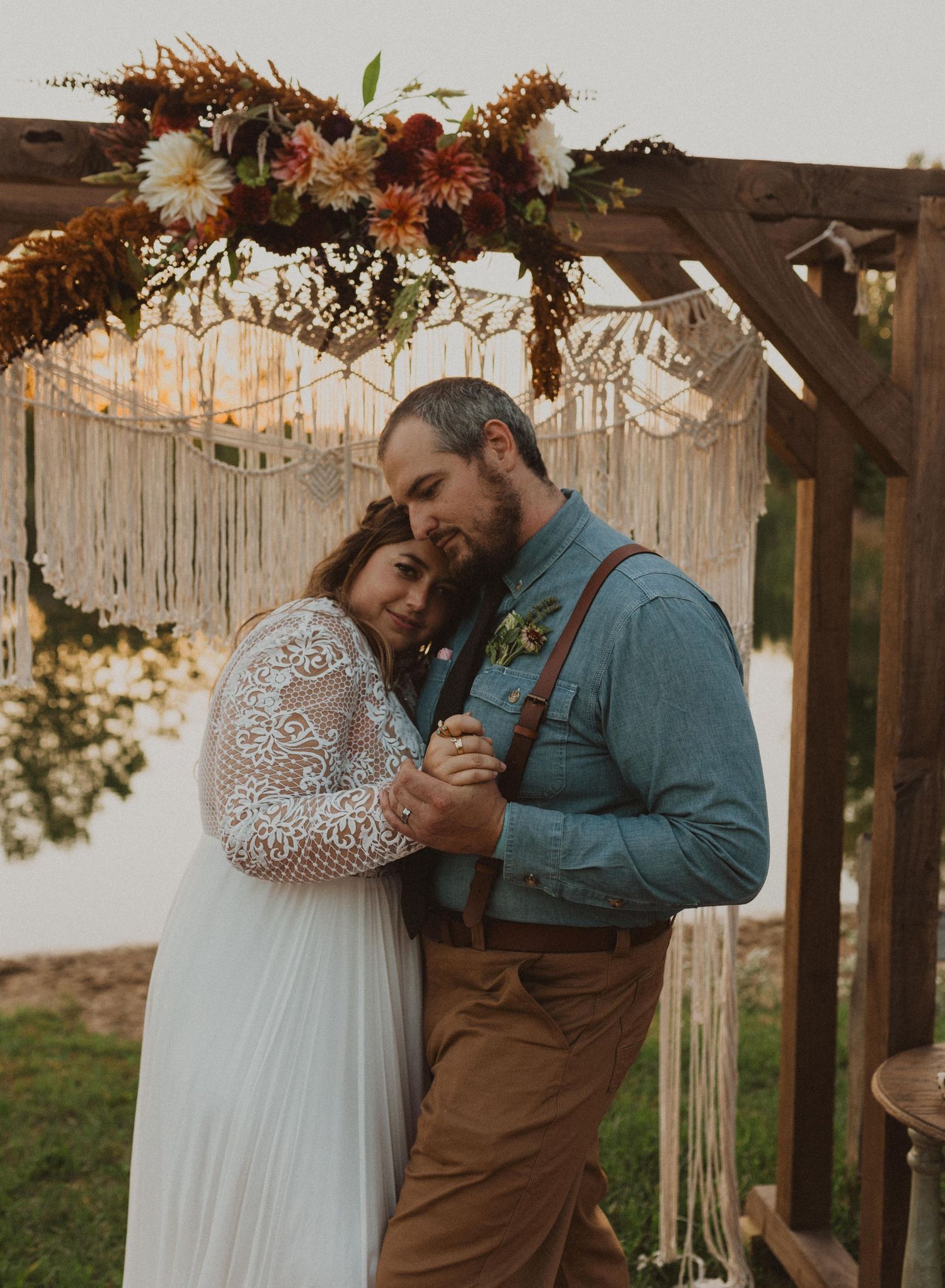 Romantic moments captured under floral-decorated pergola with macrame backdrop.