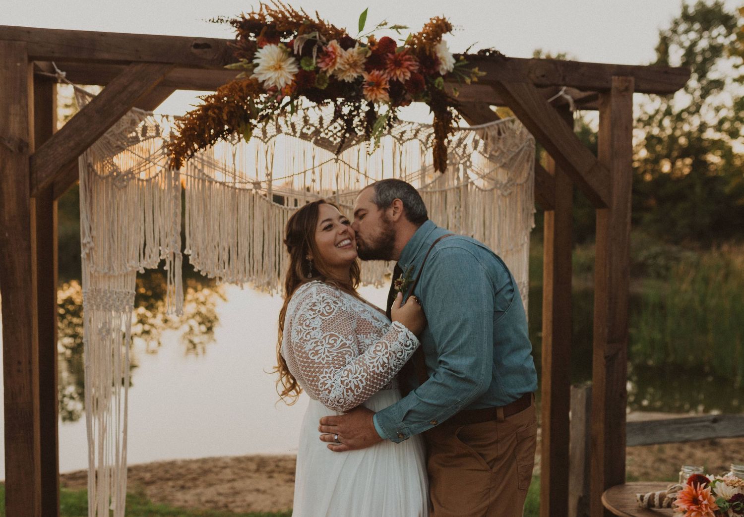 Romantic moments shared under wooden pergola with autumn floral decorations.