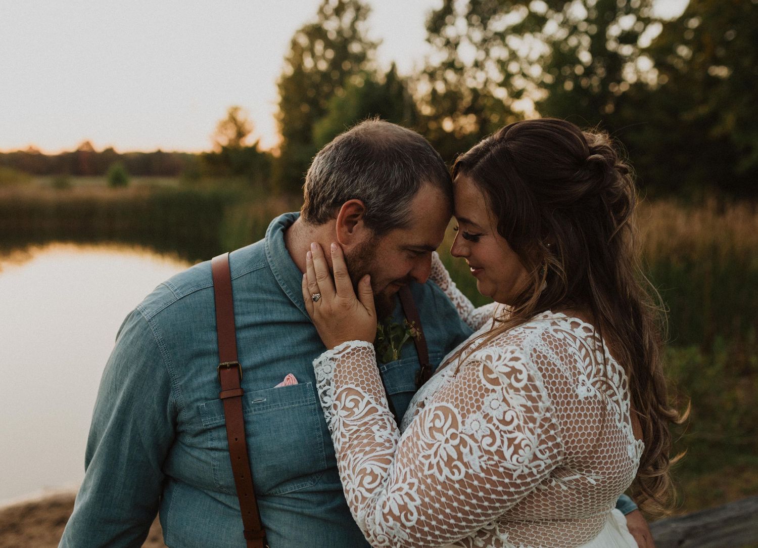 An intimate moment between newlyweds captured during golden hour by a lake.
