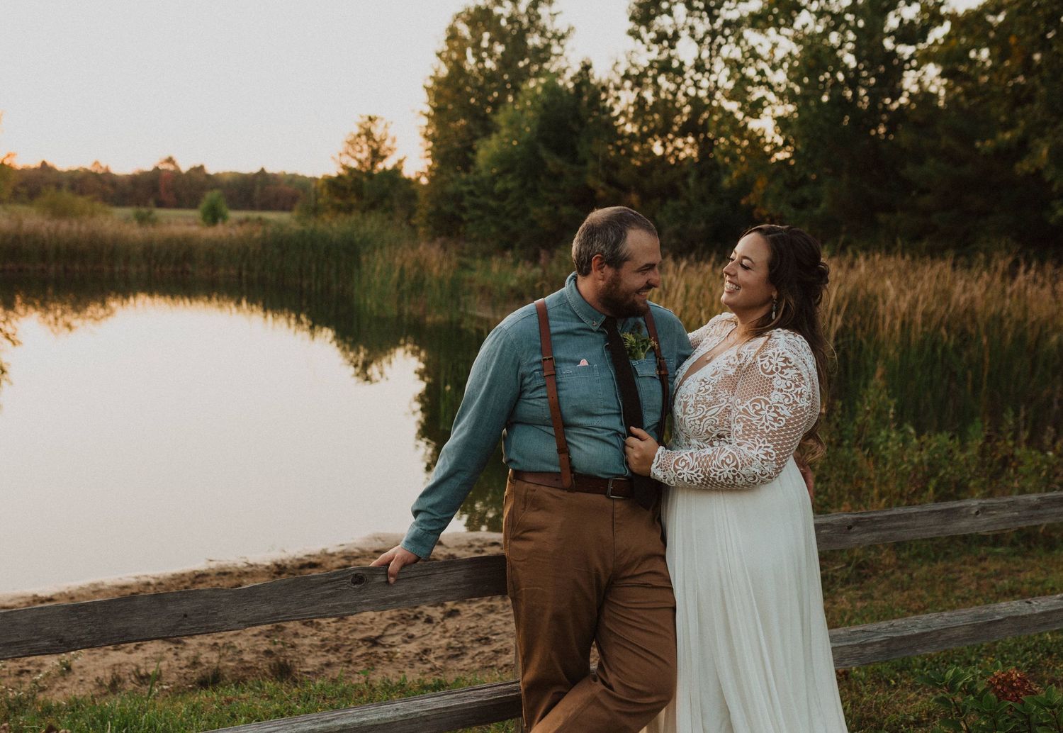 A romantic sunset photo session by a lake with a couple laughing together.