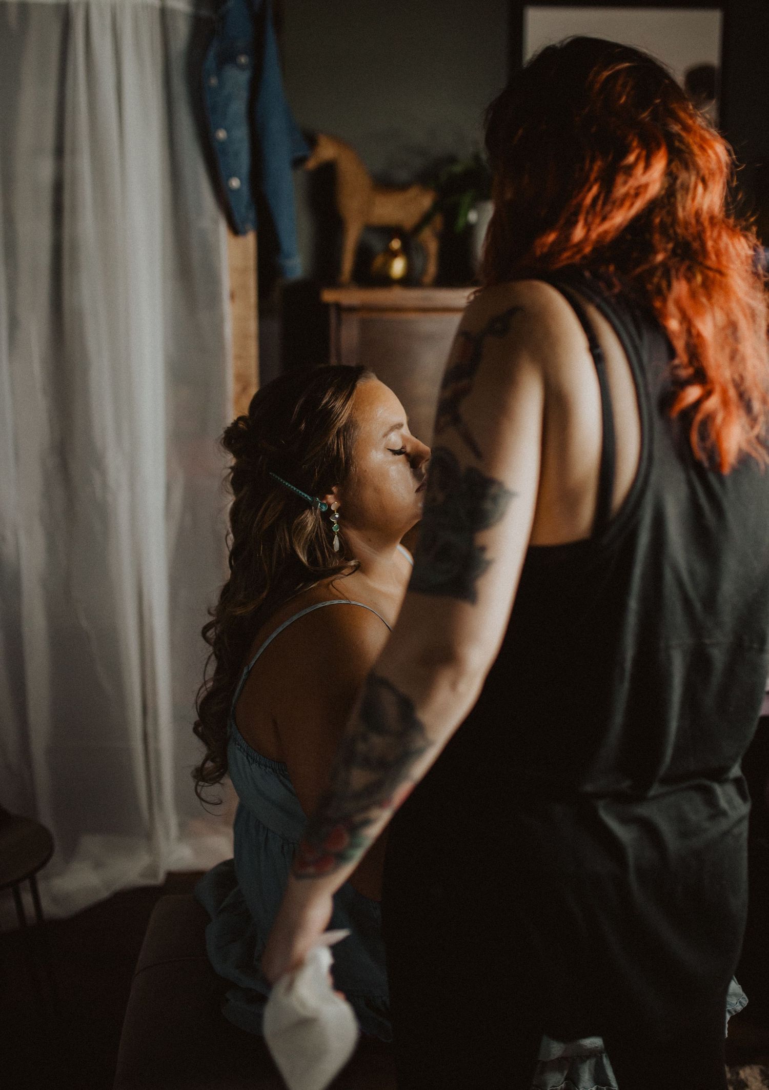 Getting ready scene with moody lighting and visible tattoos in a dressing room.