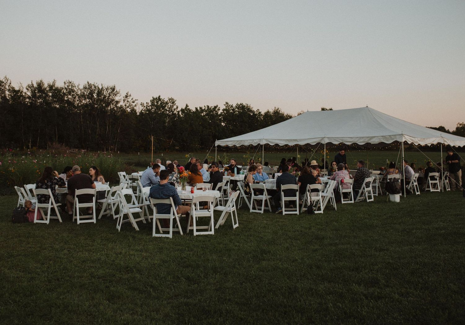 White folding chairs arranged in rows on a grassy field for an outdoor ceremony.