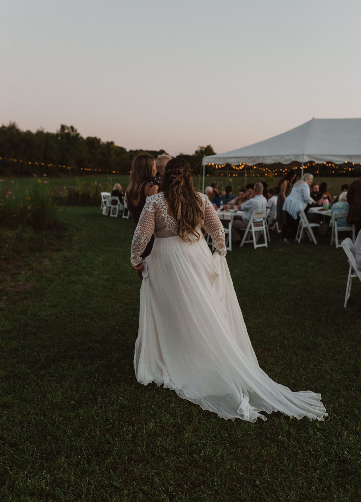 Flowing white wedding dress captured in motion during an outdoor evening celebration.
