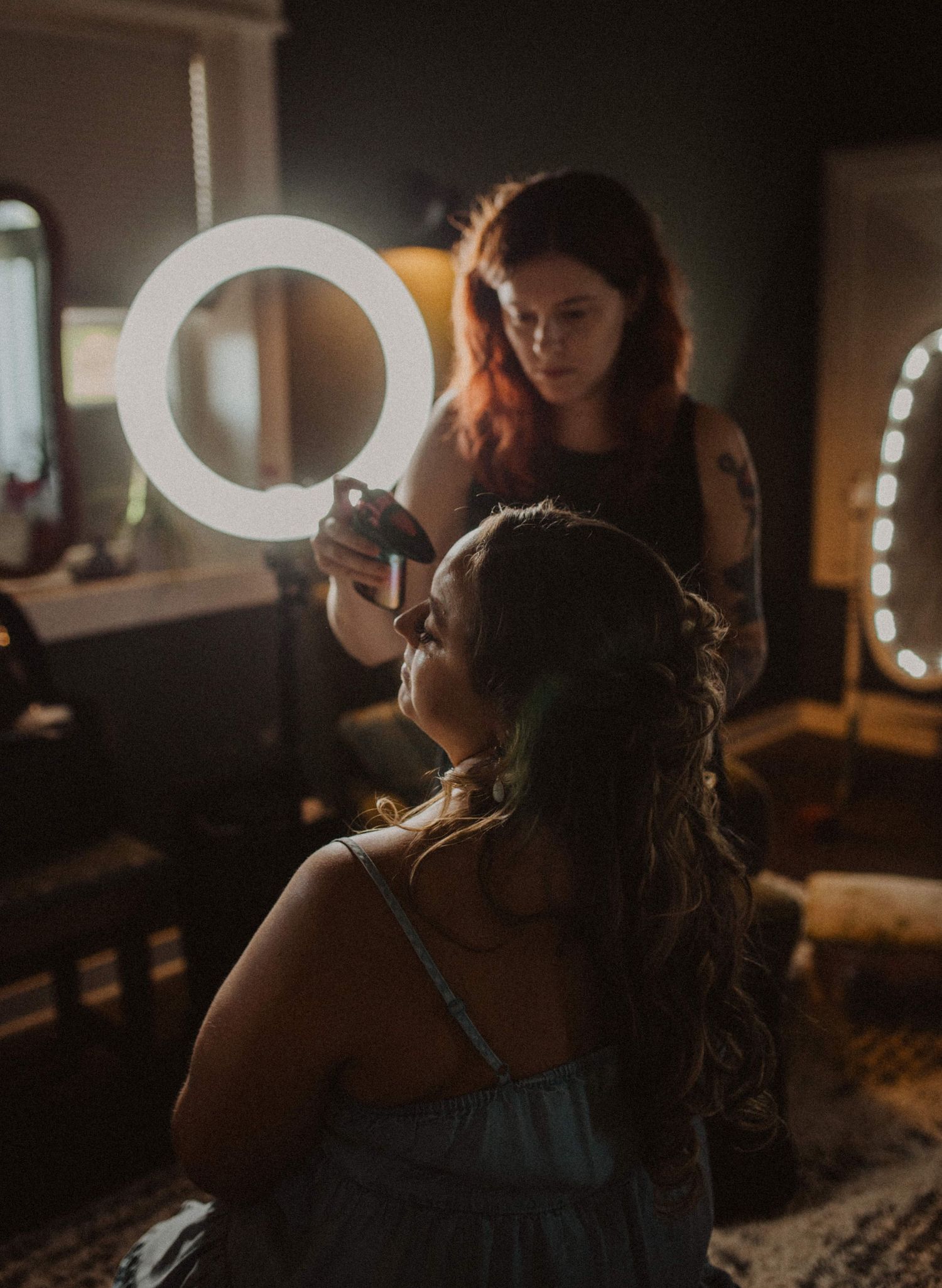 Ring light illuminates styling session in dark moody room.