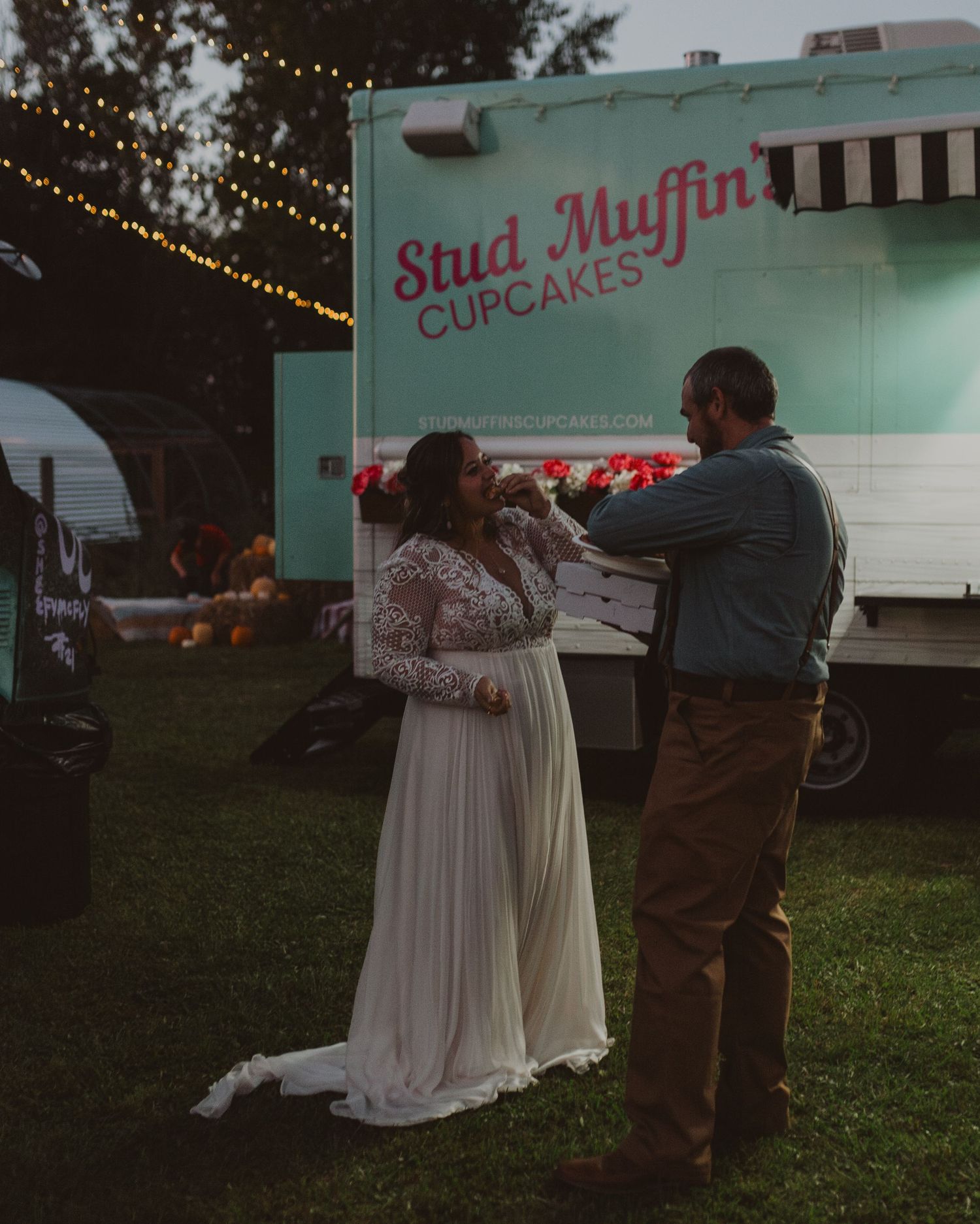 A couple stands near a mint green food truck at a casual outdoor wedding reception.