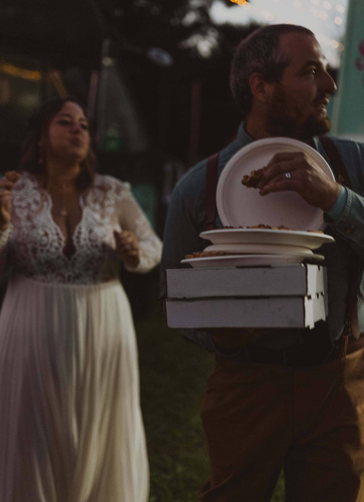 Guests enjoy food and conversation near illuminated food trucks at dusk.