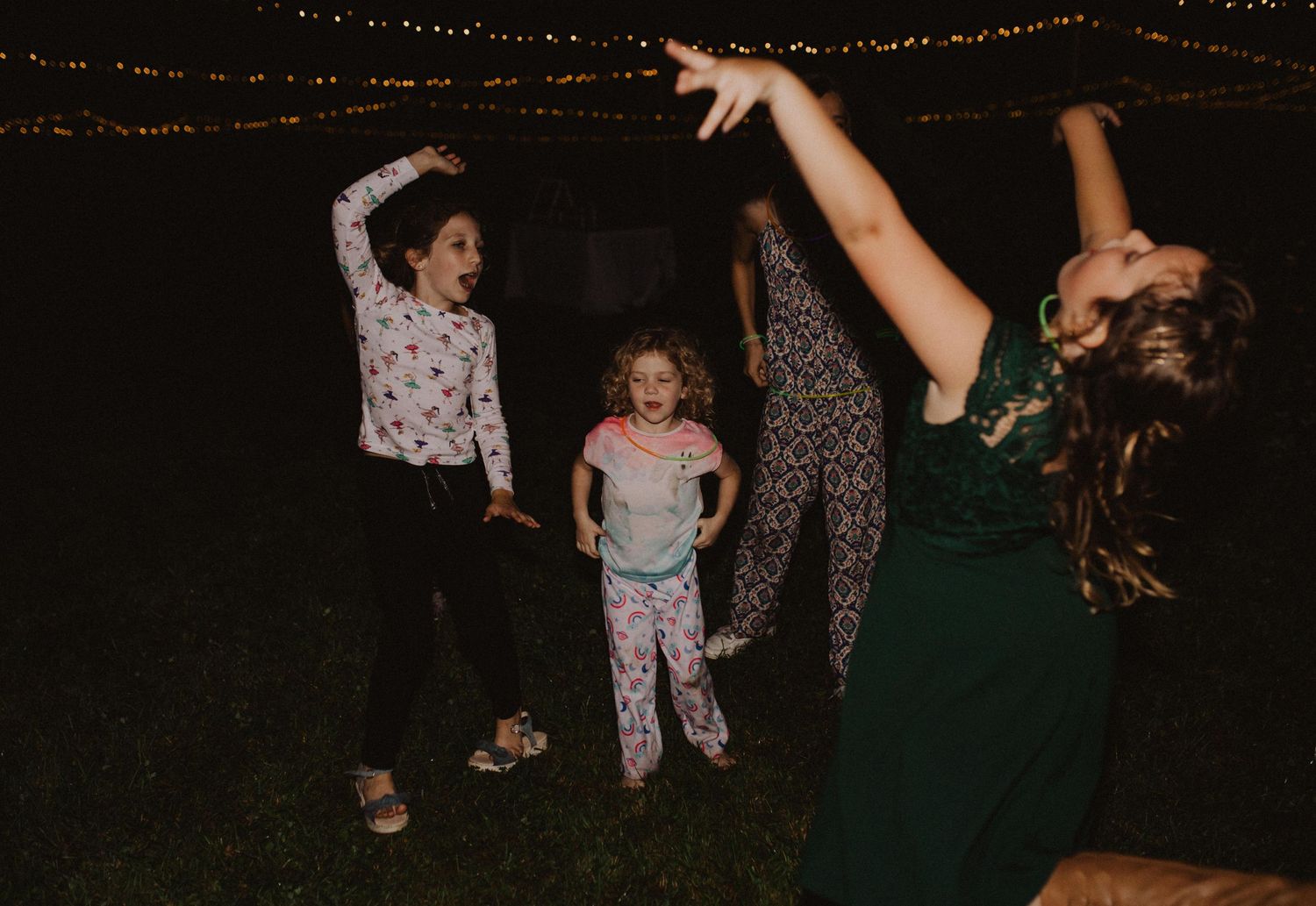 Guests dancing and celebrating under string lights at an outdoor evening party.