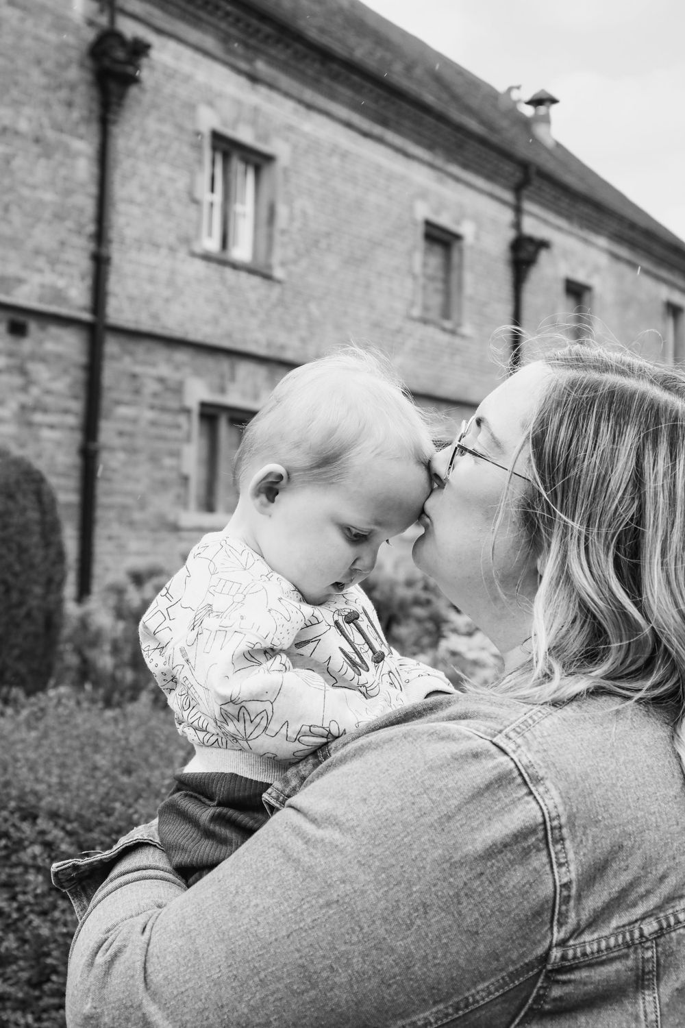 Black and white portrait of tender moment between parent and baby outdoors.