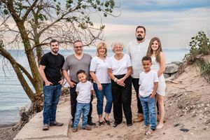 A multi-generational family poses together on a beach with Lake Michigan in the background.