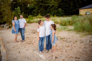 Groups of people standing on a sandy beach path during golden hour.