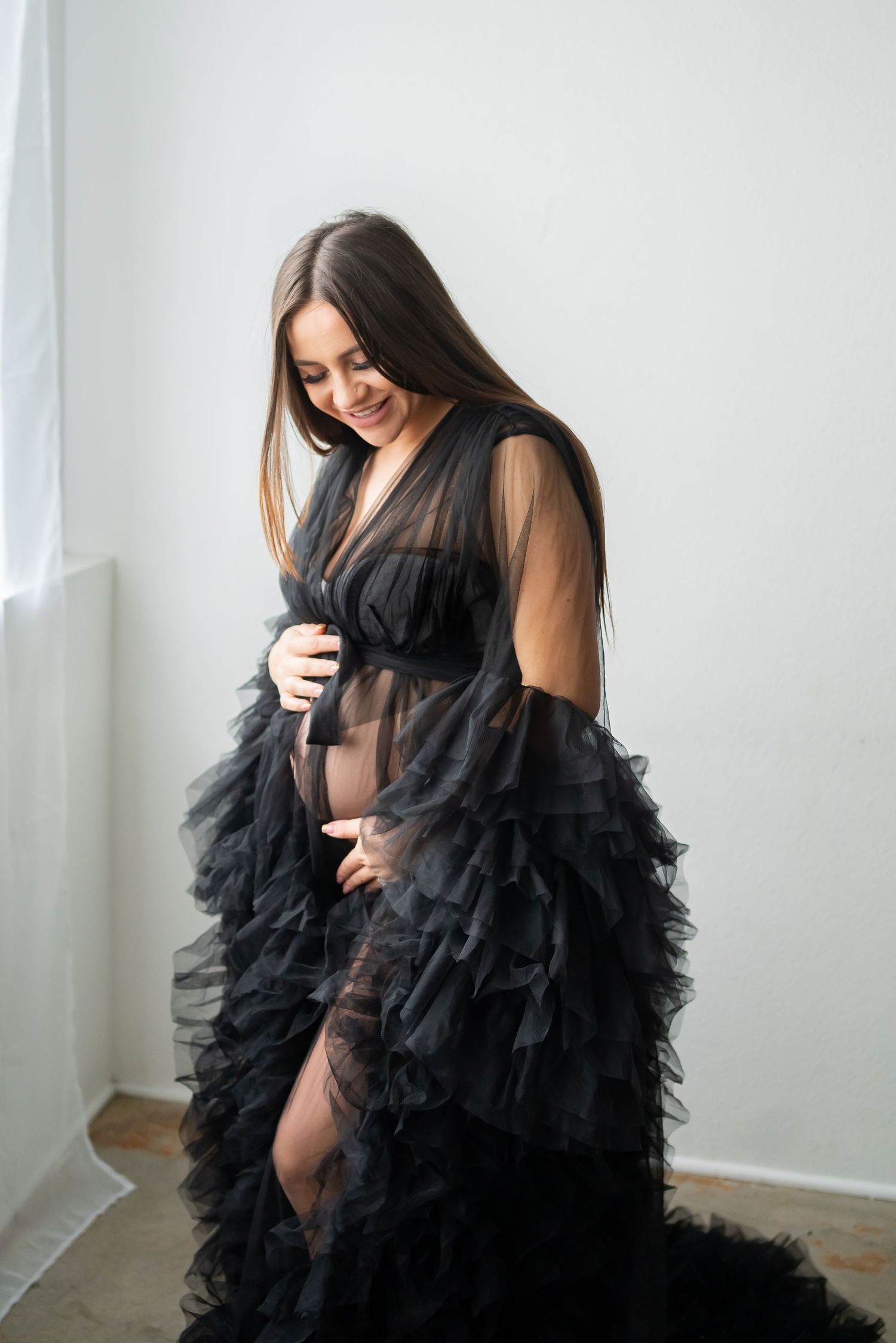 Intimate maternity portrait featuring sheer black tulle gown with cascading ruffles.