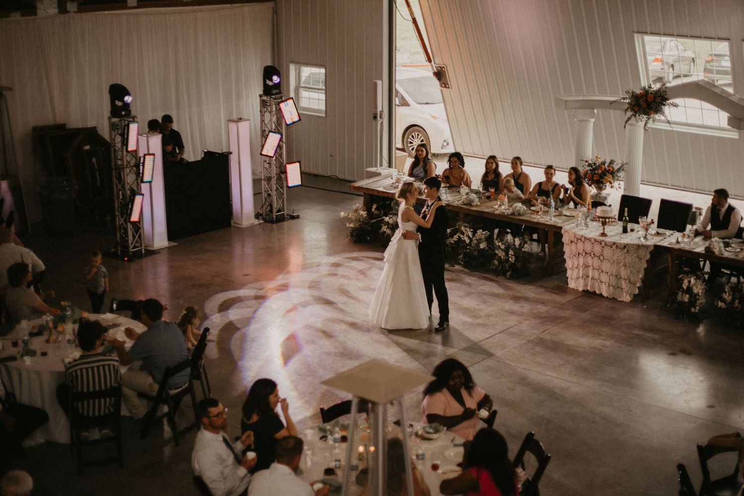 A first dance moment at a wedding reception in a rustic barn venue with guests watching.