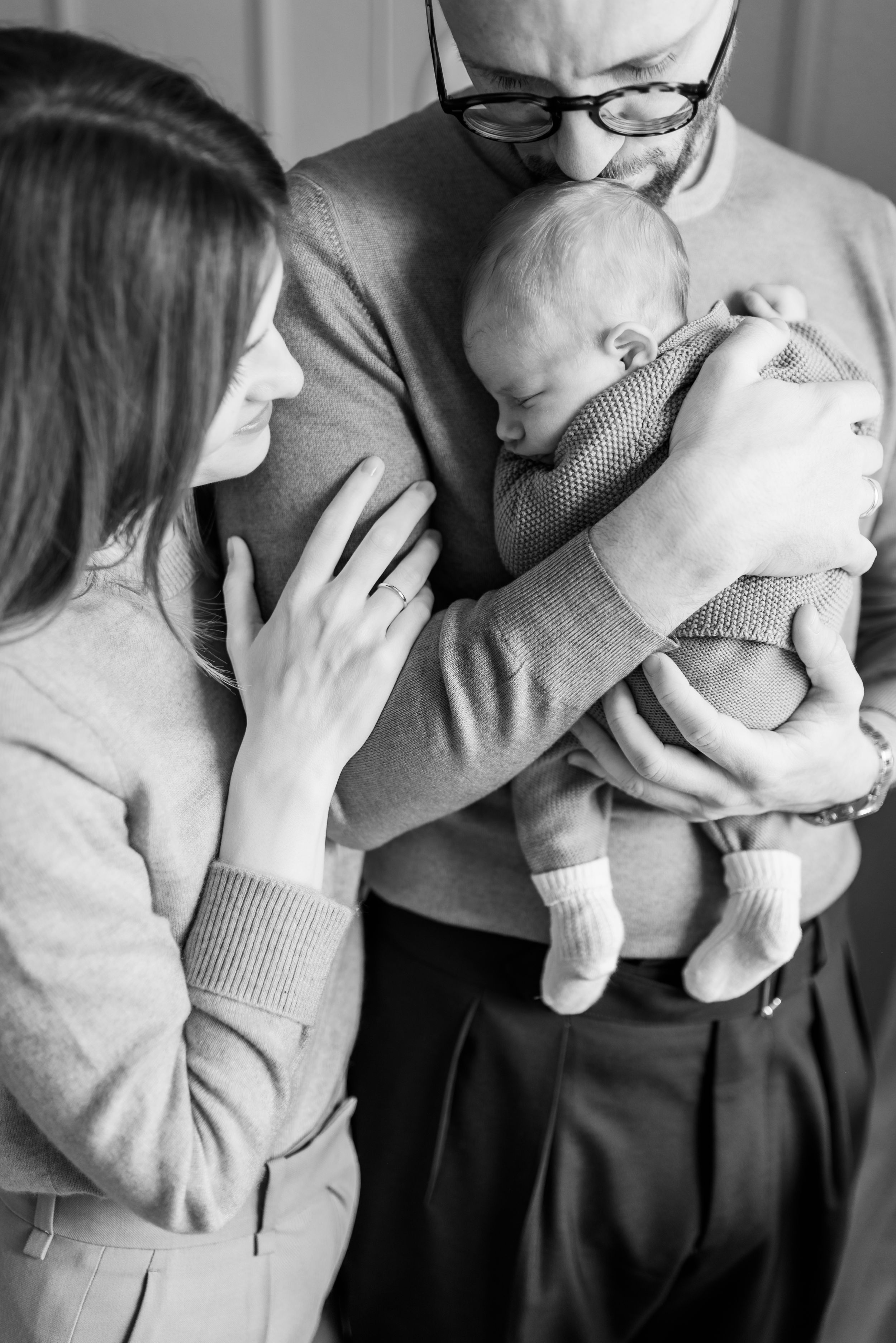 Black and white portrait of parents sharing a tender moment with their sleeping baby.