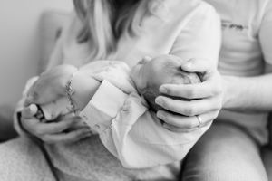 Black and white photo of hands cradling a newborn baby.